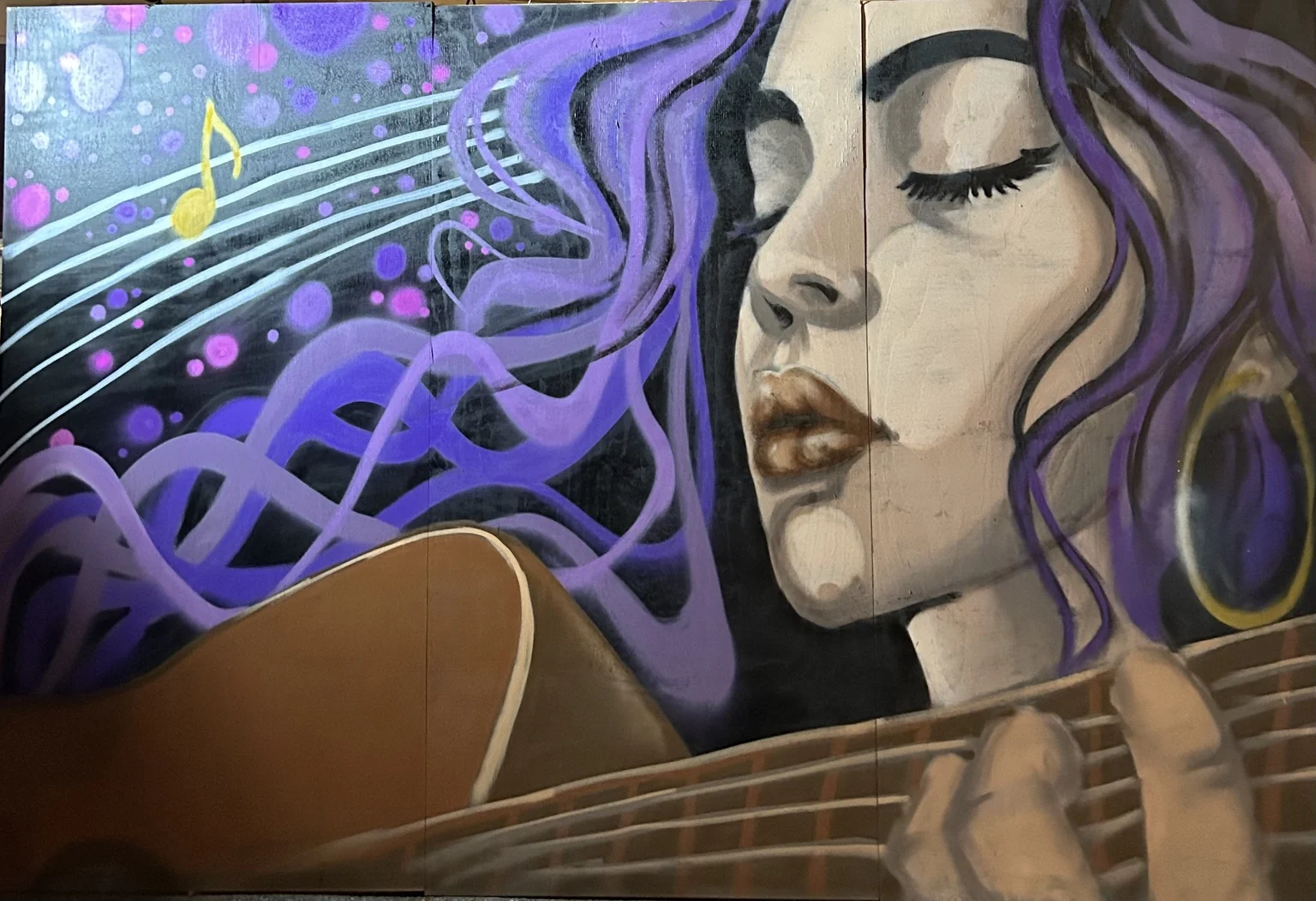ARES mural of a woman with purple hair playing guitar, surrounded by musical notes